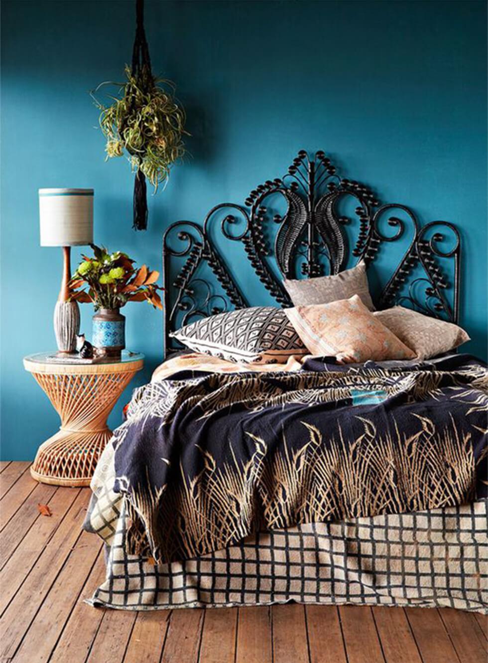Teal bedroom with a rattan side table and ornate peacock rattan bed