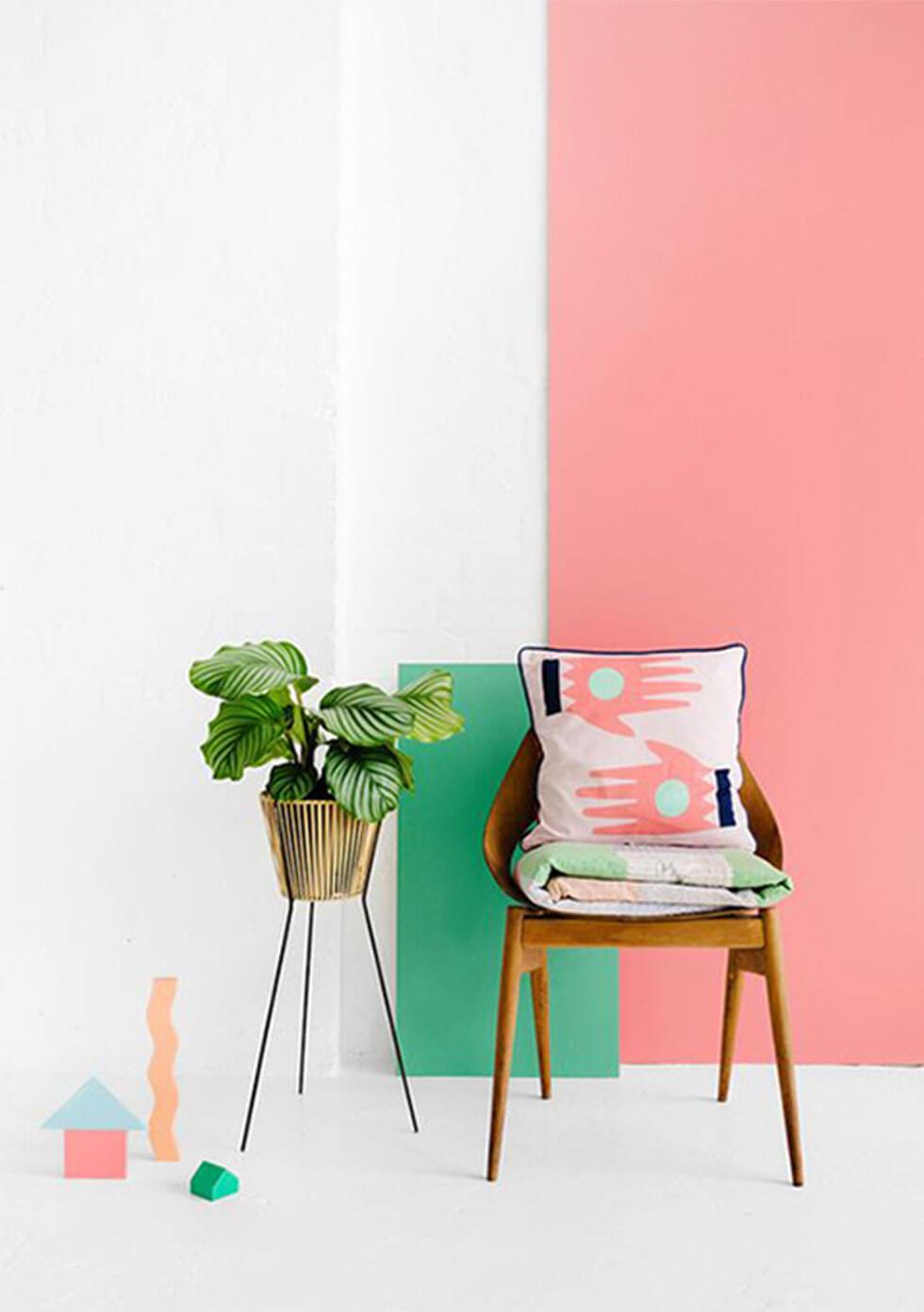 wooden chair against an energising neo-mint and coral pink wall.