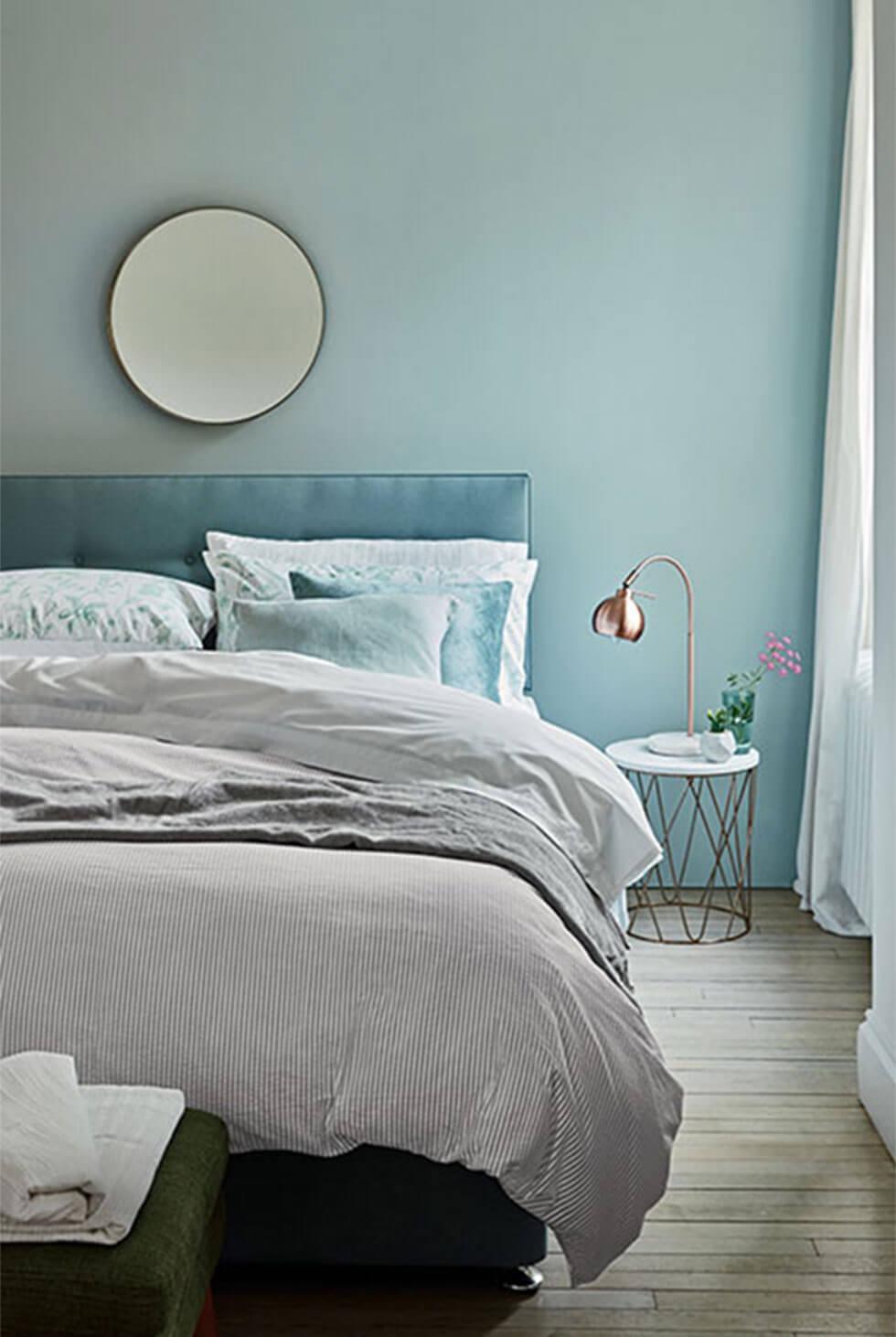 Calm, blue modern bedroom in tonal shades and soft bedding