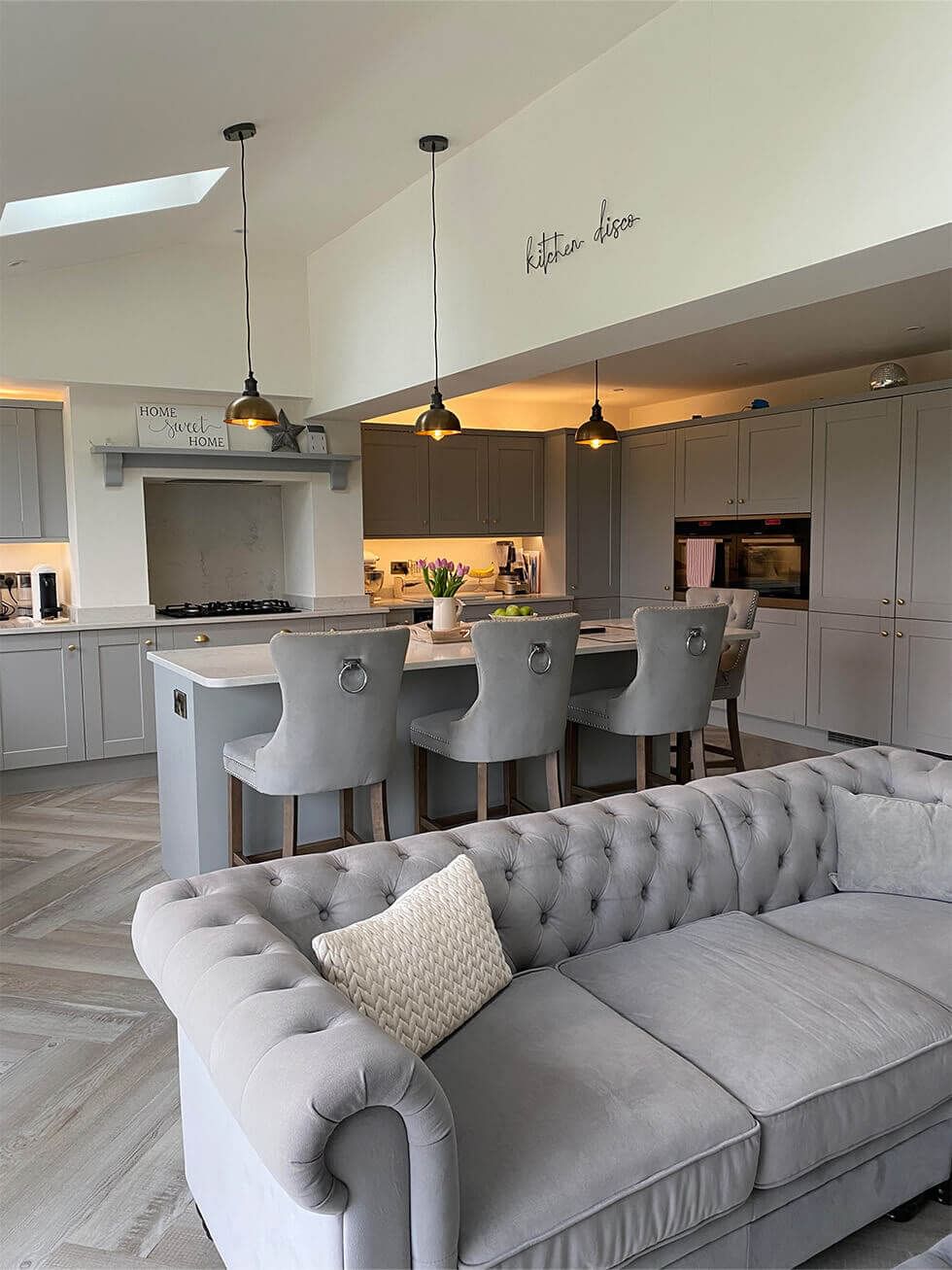 Modern open plan kitchen with an island, bar stools, and a sofa